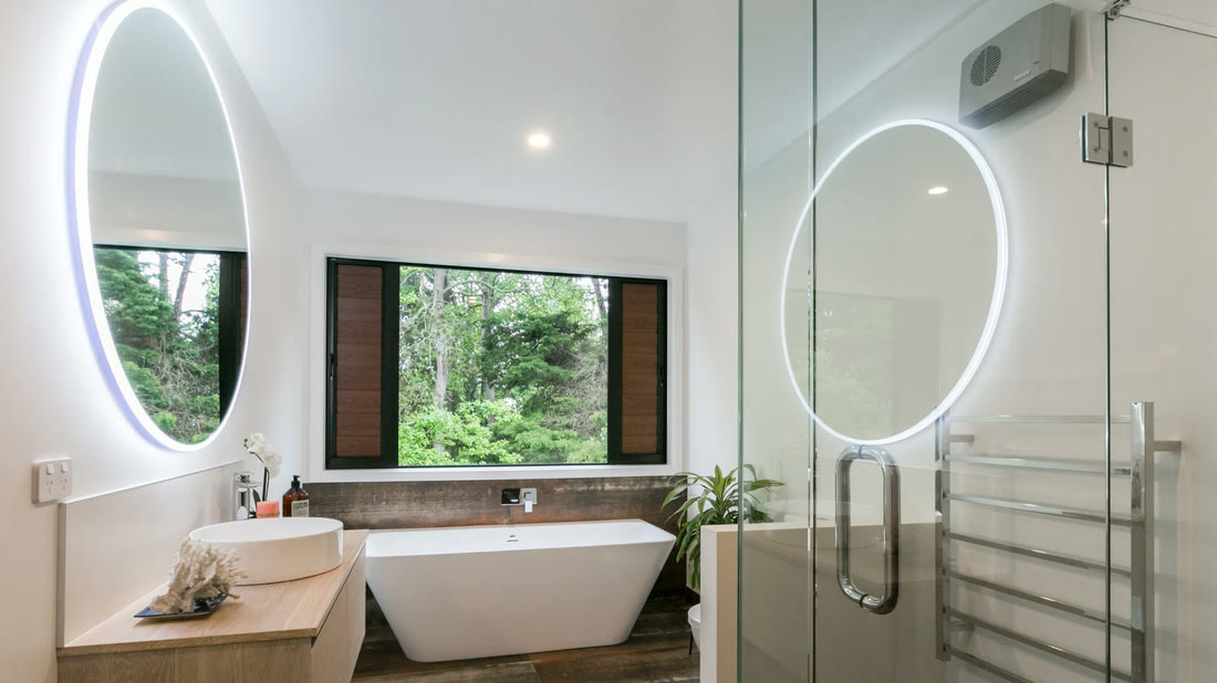 Bathroom with a freestanding tub and twin backlit mirrors